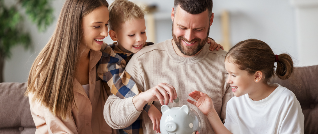 family of four putting money into piggy bank